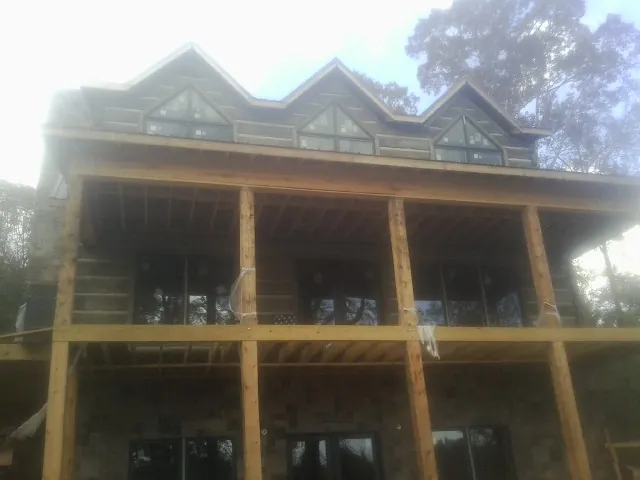 Dormers and porch framing on a large log home under construction — Roof Coating work by our crew in Fort Mc Coy
