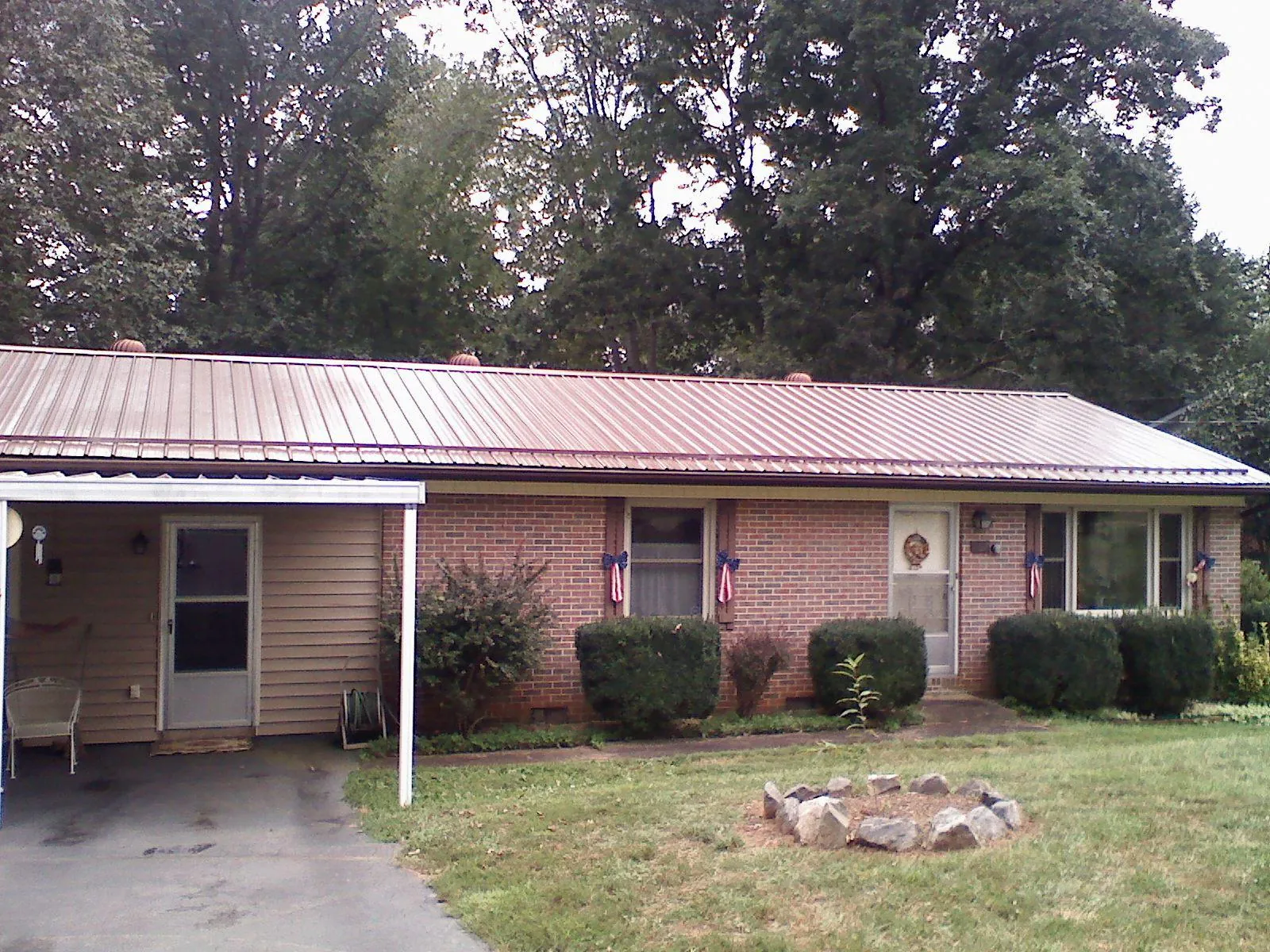 Bronze metal roof and carport on a brick ranch home — Roof Repair work by our crew in Fort Mc Coy
