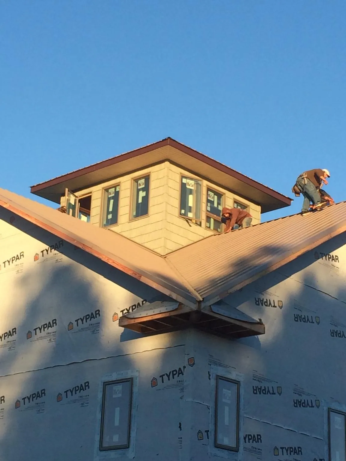 Roofers working around a rooftop cupola on a new metal roof at sunset — Roof Waterproofing in Fort Mc Coy by Roofing Brothers